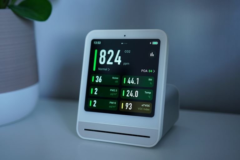 Close-up of a digital air quality monitor displaying CO2, PM2.5, and temperature readings.